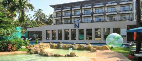 A hotel with a pool area, palm trees, and a large inflatable ball.