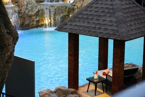 A wooden gazebo with a tiled roof overlooking a pool with a waterfall in the background. - Novotel Goa Candolim Hotel (Candolim)