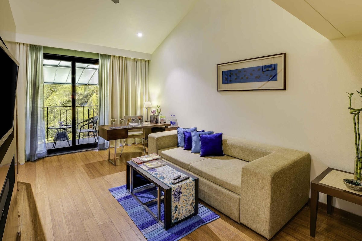 A living room with a sofa, coffee table, and a dining area with a table and chairs.