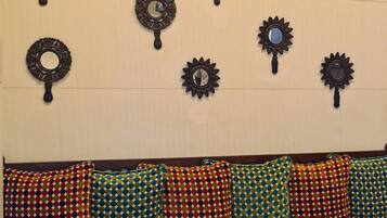 A room with a green sofa, colorful patterned cushions, and wall-mounted decorative mirrors.