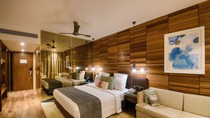 Ein modernes Hotelzimmer mit einem großen Bett, einer Couch, einem Schreibtisch und einem Spiegel.