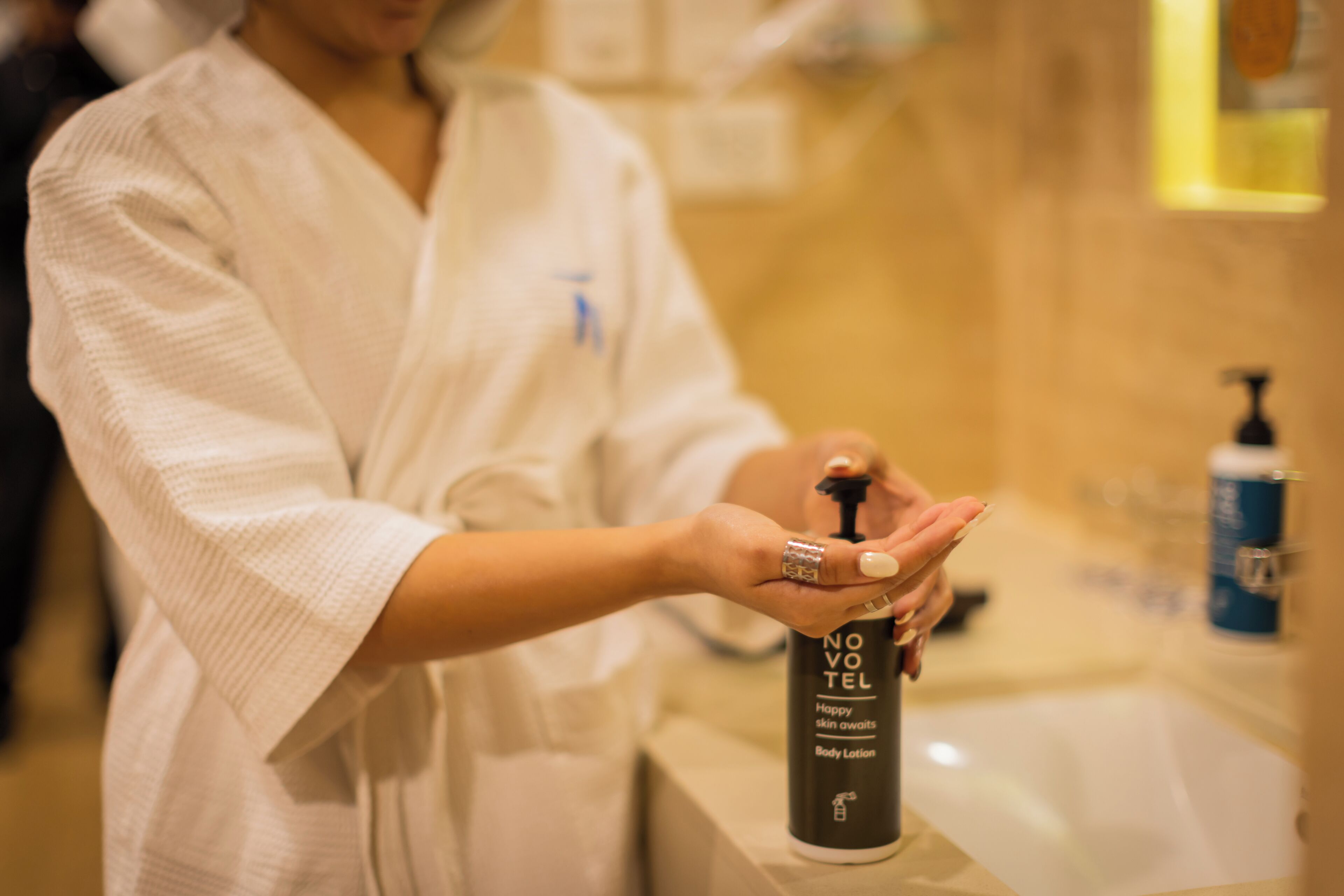 Une personne vêtue d’une robe qui verse une lotion d’un flacon.