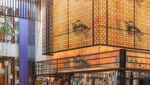 Eine Bar mit Hockstühlen, einer Theke mit Flaschen und einer Zierte Decke.