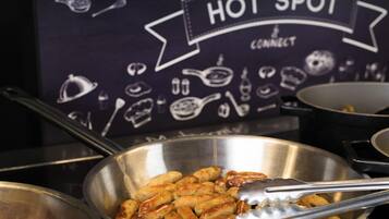 A kitchen area with a sign reading 'HOT SPOT CONNECT' and a bowl of cooked sausages.