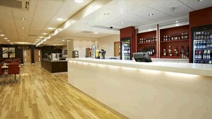 A modern bar area with a counter, seating, and a variety of liquor bottles. - Travelodge Manchester Piccadilly (Manchester)