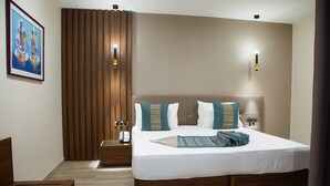 Habitación de hotel ordenada con una cama grande, una mesita de noche y un banco de madera.