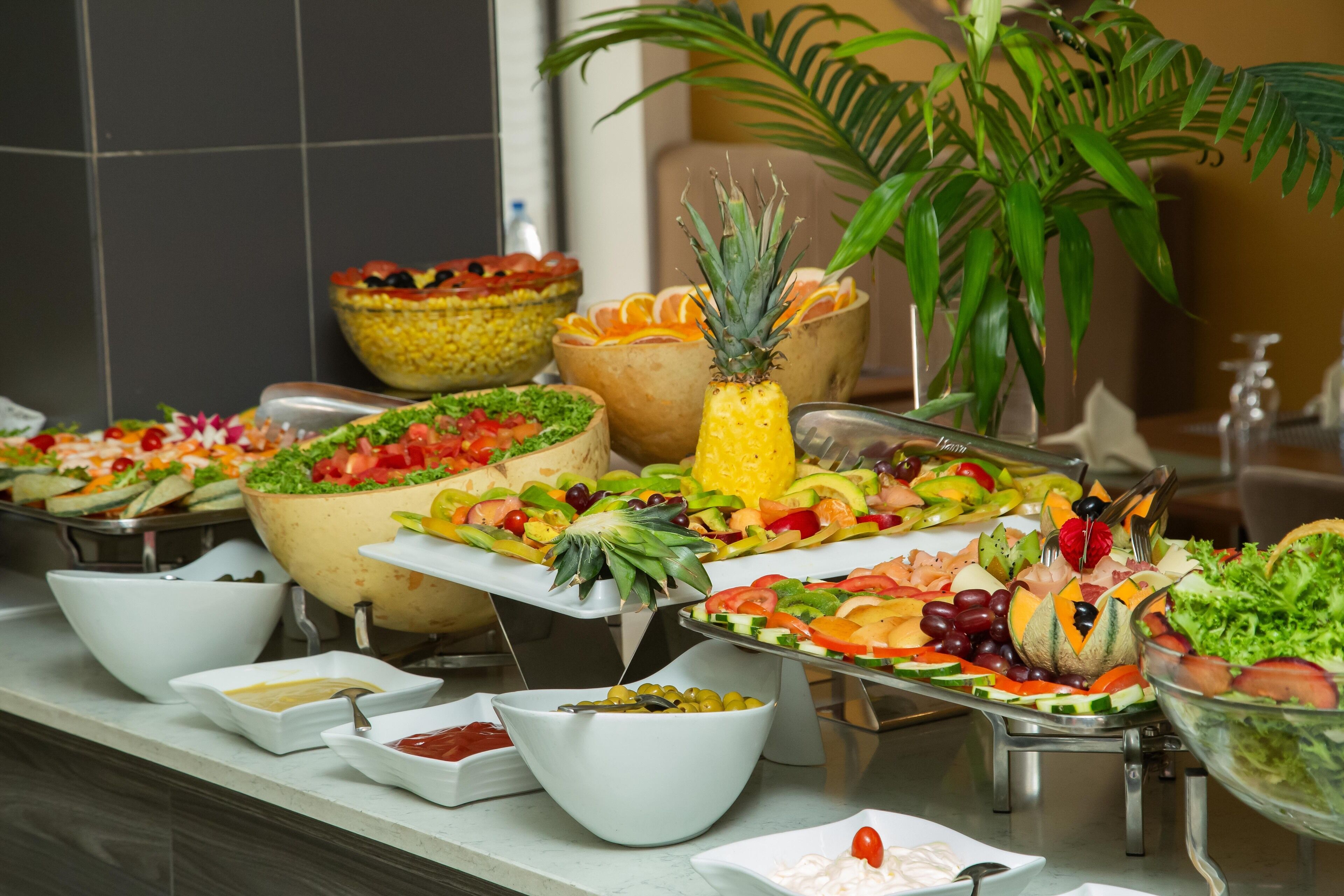 Un bufé con diversos platos, entre ellos ensaladas, frutas y verduras.