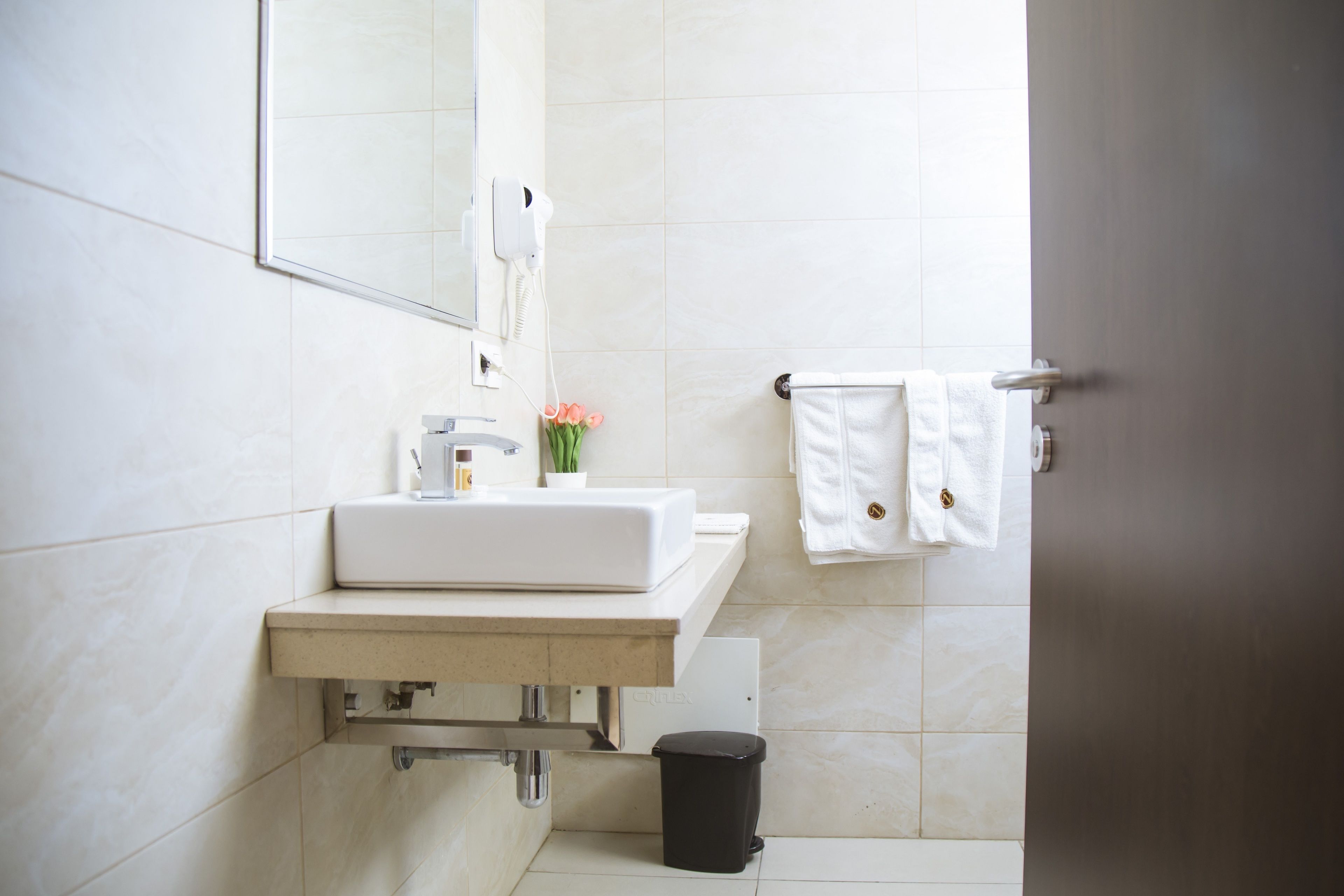 A bathroom with a white sink, mirror, and towel rack.