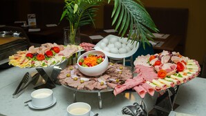 Un bufé con diversos alimentos, como carnes, quesos y ensaladas, sobre un soporte metálico.