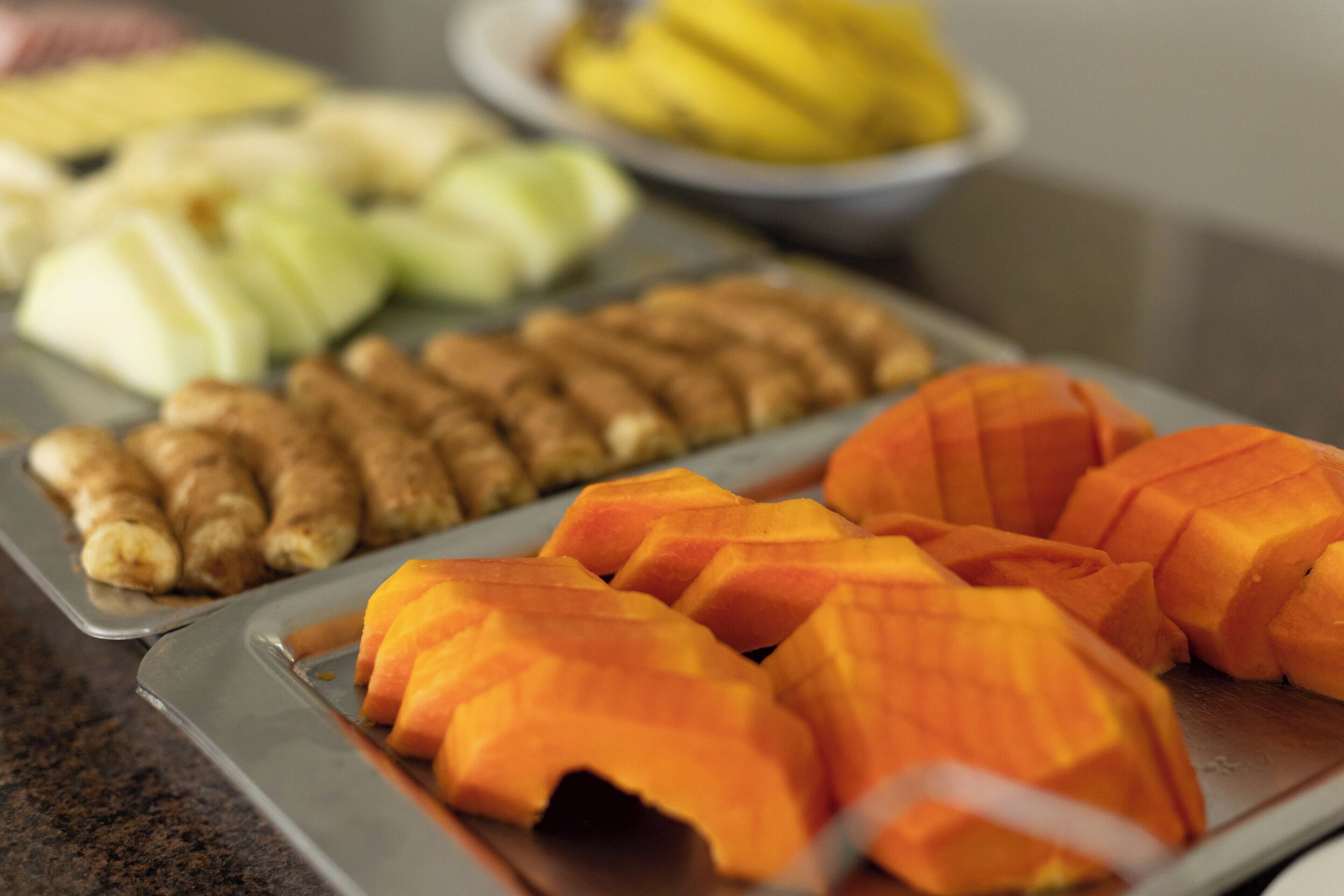 Una bandeja con frutas cortadas, entre ellas mangos, manzanas y jengibre.