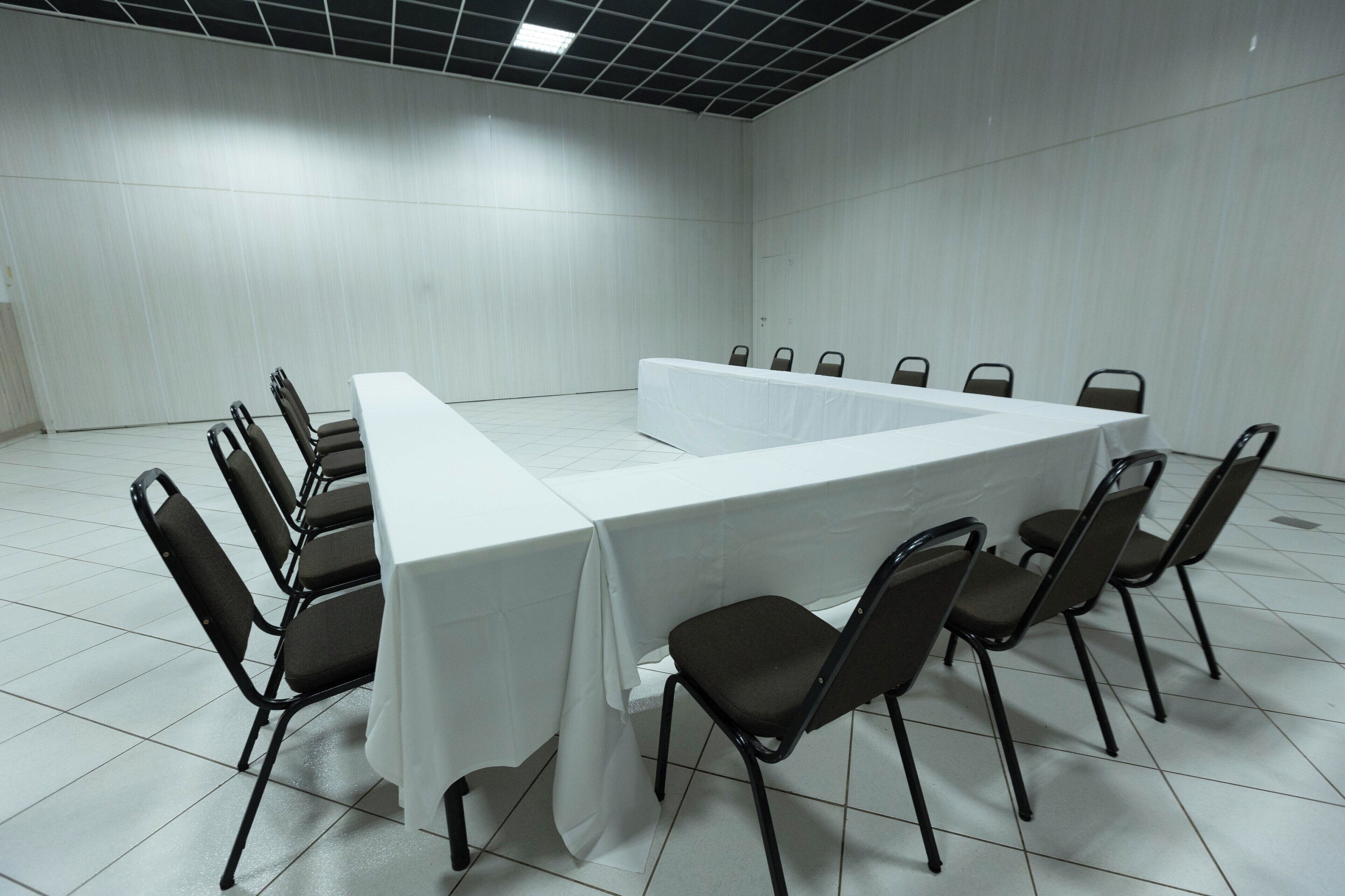 Un salón de conferencias con una mesa larga y sillas dispuestas alrededor.