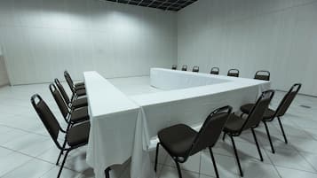 Un salón de conferencias con una mesa larga y sillas dispuestas alrededor.