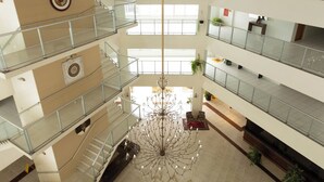 A multi-level atrium with glass railings, a central chandelier, and a geometric floor design. - HITS PANTANAL HOTEL AEROPORTO (Varzea Grande)