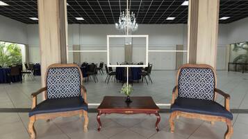 Una habitación con dos sillas de madera con cojines azules, una mesa de madera con un jarrón y una araña.