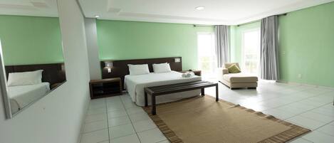 A hotel room with a large bed, a bedside table, a chair, and a window with curtains.