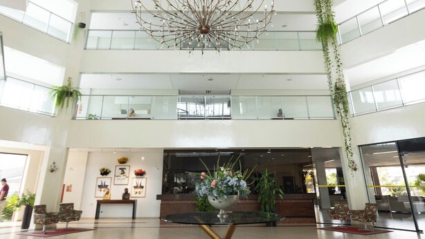 A spacious lobby with a high ceiling, a central chandelier, and multiple floors with glass railings. - HITS PANTANAL HOTEL AEROPORTO (Varzea Grande)