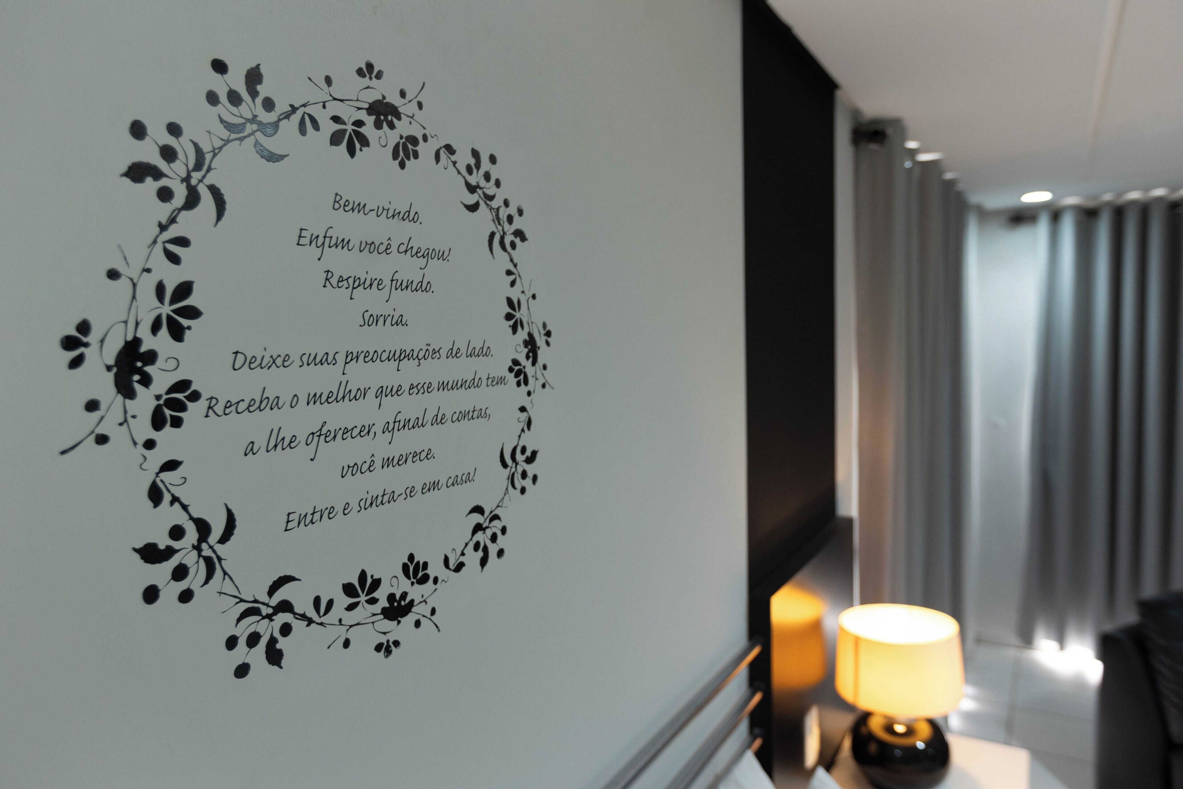 A wall with a floral design and a welcoming message in Portuguese.