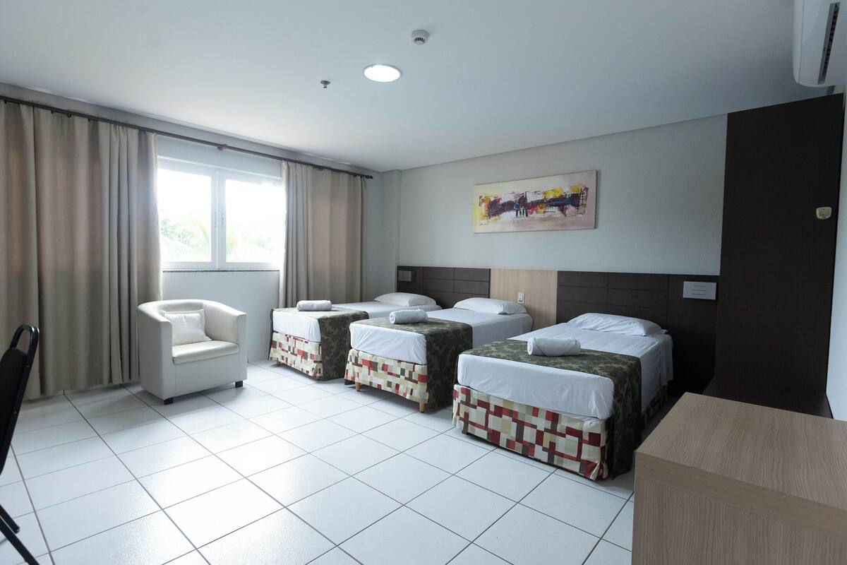 A hotel room with a bed, a chair, and a small table.