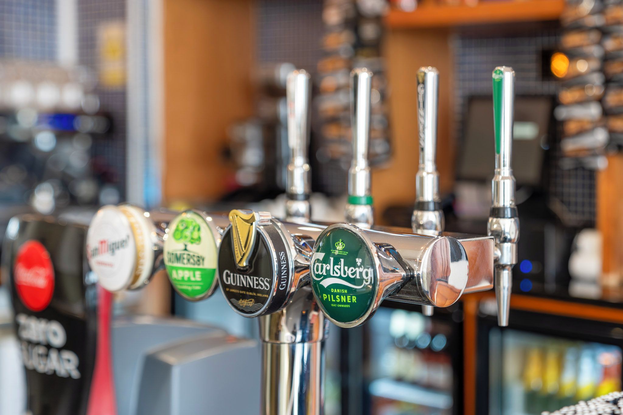 Um bar com diversas torneiras de cerveja, incluindo marcas como Guinness e Carlsberg.