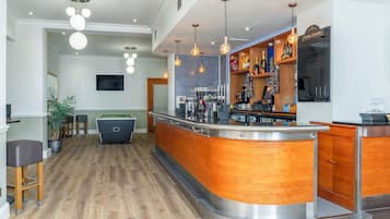 A modern bar area with a pool table, wooden bar counter, and hanging pendant lights.