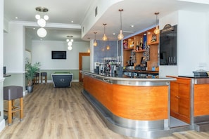 Un espace bar moderne avec un billard, un comptoir en bois et des lampes suspendues.