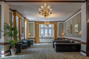 Une pièce décorée d’un lustre, de canapés en cuir, d’une grande plante en pot et d’un tapis à motifs.