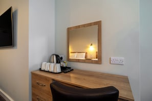 A hotel room with a wooden desk, a black leather chair, a coffee maker, a tray with cups and a remote control, and a mirror on the wall. - North Stafford Britannia (Stoke-on-Trent)