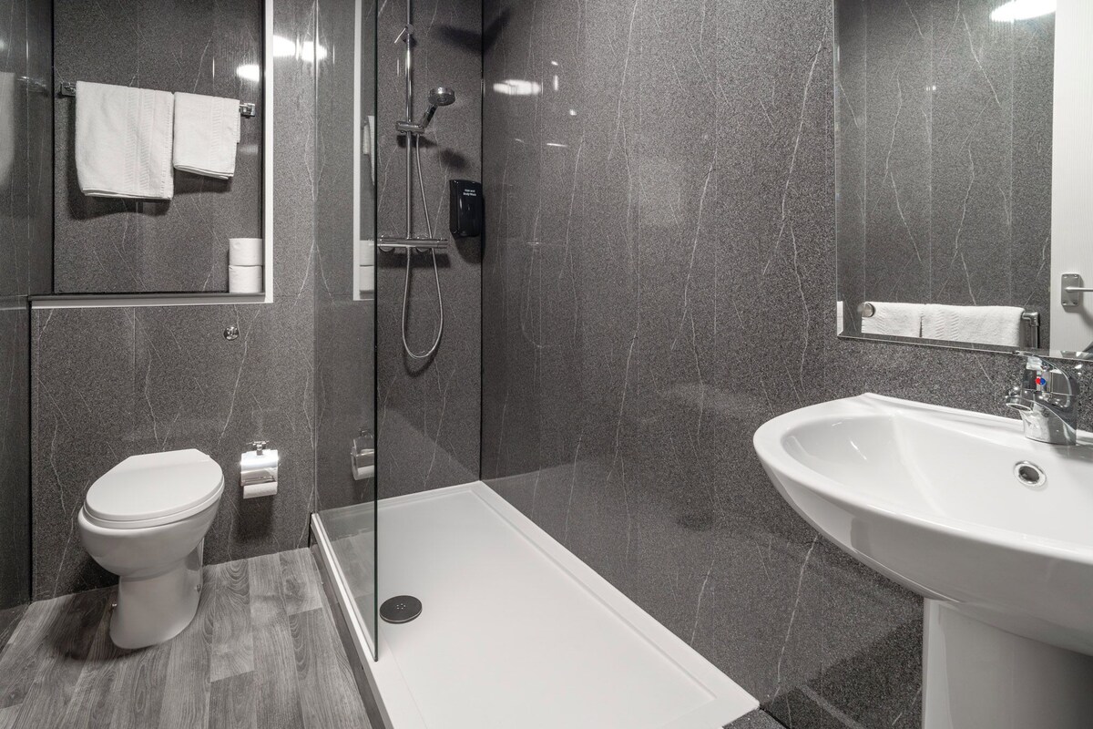Une salle de bain moderne équipée de toilettes, d’une douche et d’un lavabo.