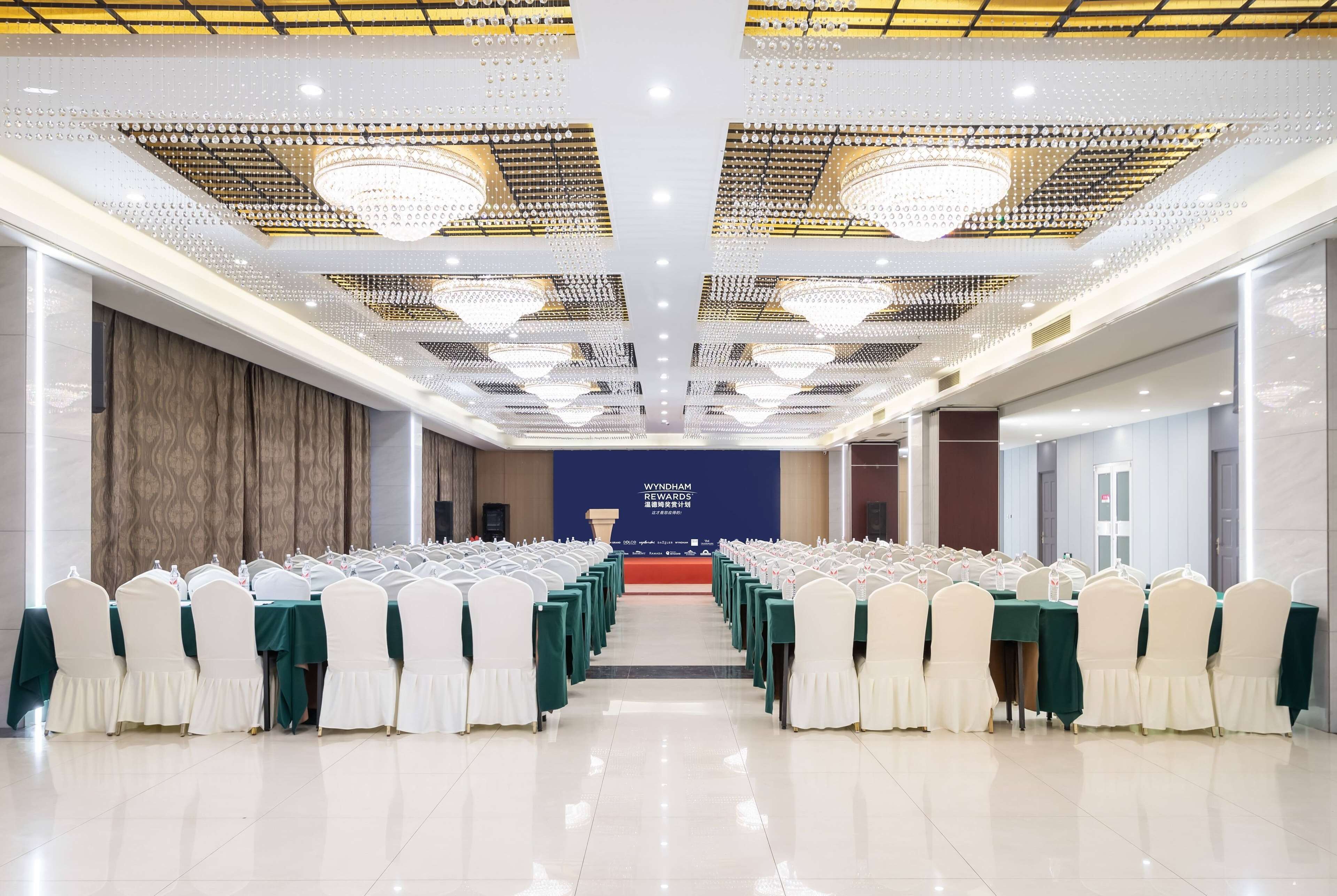 A conference room with rows of tables and chairs, a podium, and a banner reading "Wyndham Rewards".