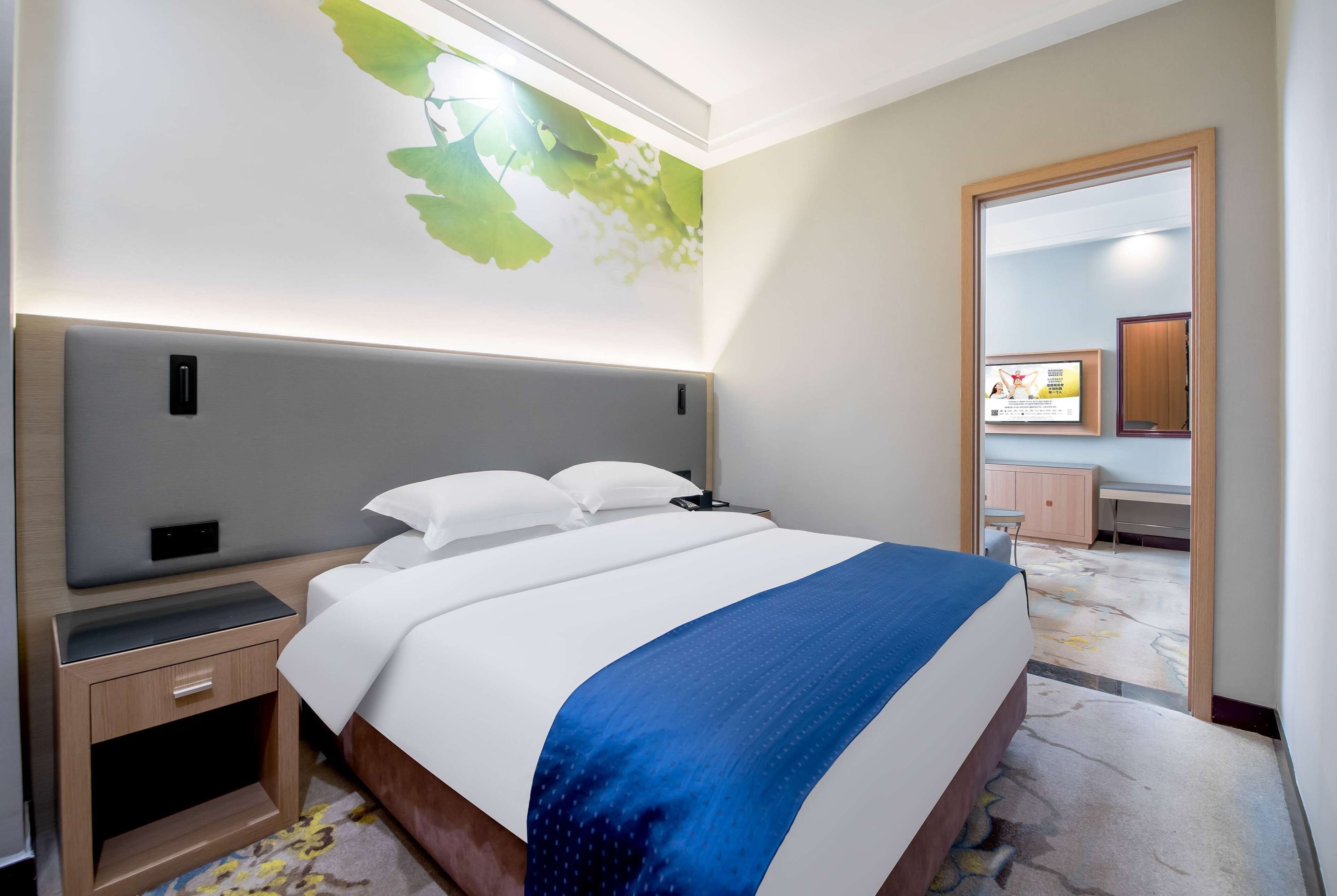 A hotel room with a bed, bedside table, and a wall-mounted artwork.