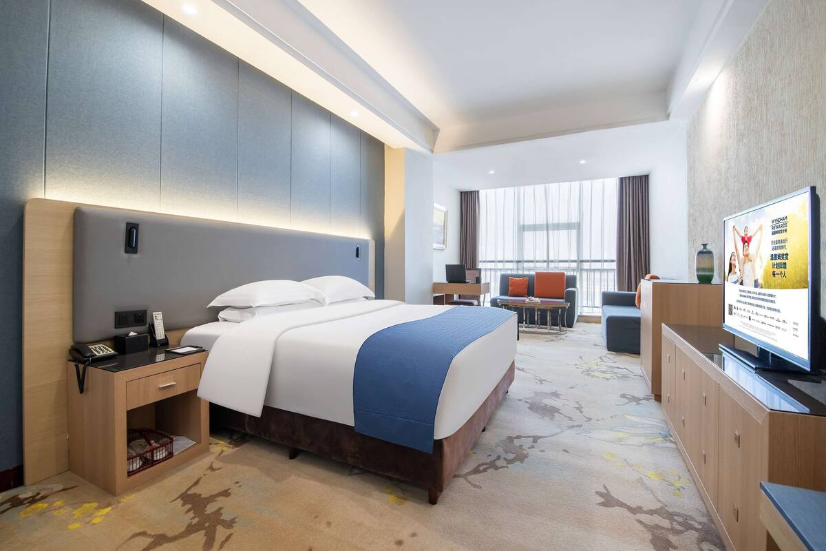 Habitación de hotel con una cama grande, una mesita de noche y un televisor.
