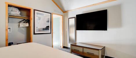 Une chambre d’hôtel avec un grand lit, une armoire en bois, un téléviseur à écran plat et un tableau encadré au mur.