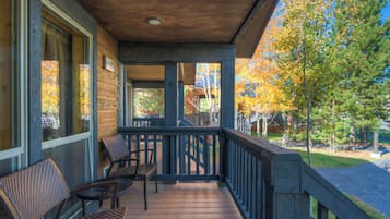 A wooden deck with outdoor seating and a view of trees in autumn colors.