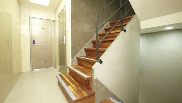 A modern interior with a wooden staircase, a glass elevator, and a tiled floor. - 24guesthouse Seoul Station (Seoul)
