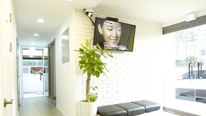 A reception area with a white brick wall, a mounted TV, a potted plant, and a bench. - 24guesthouse Seoul Station (Seoul)