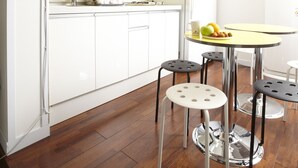 A modern kitchen with white cabinets, a yellow backsplash, and a round table with stools. - 24guesthouse Seoul Station (Seoul)