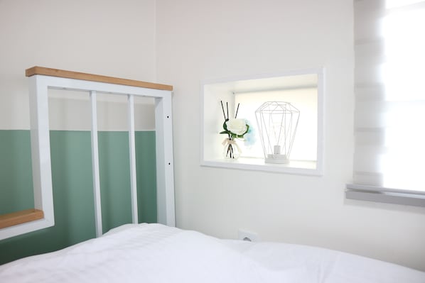 Une chambre à coucher avec un lit, une fenêtre donnant sur un beau paysage et un mur blanc.