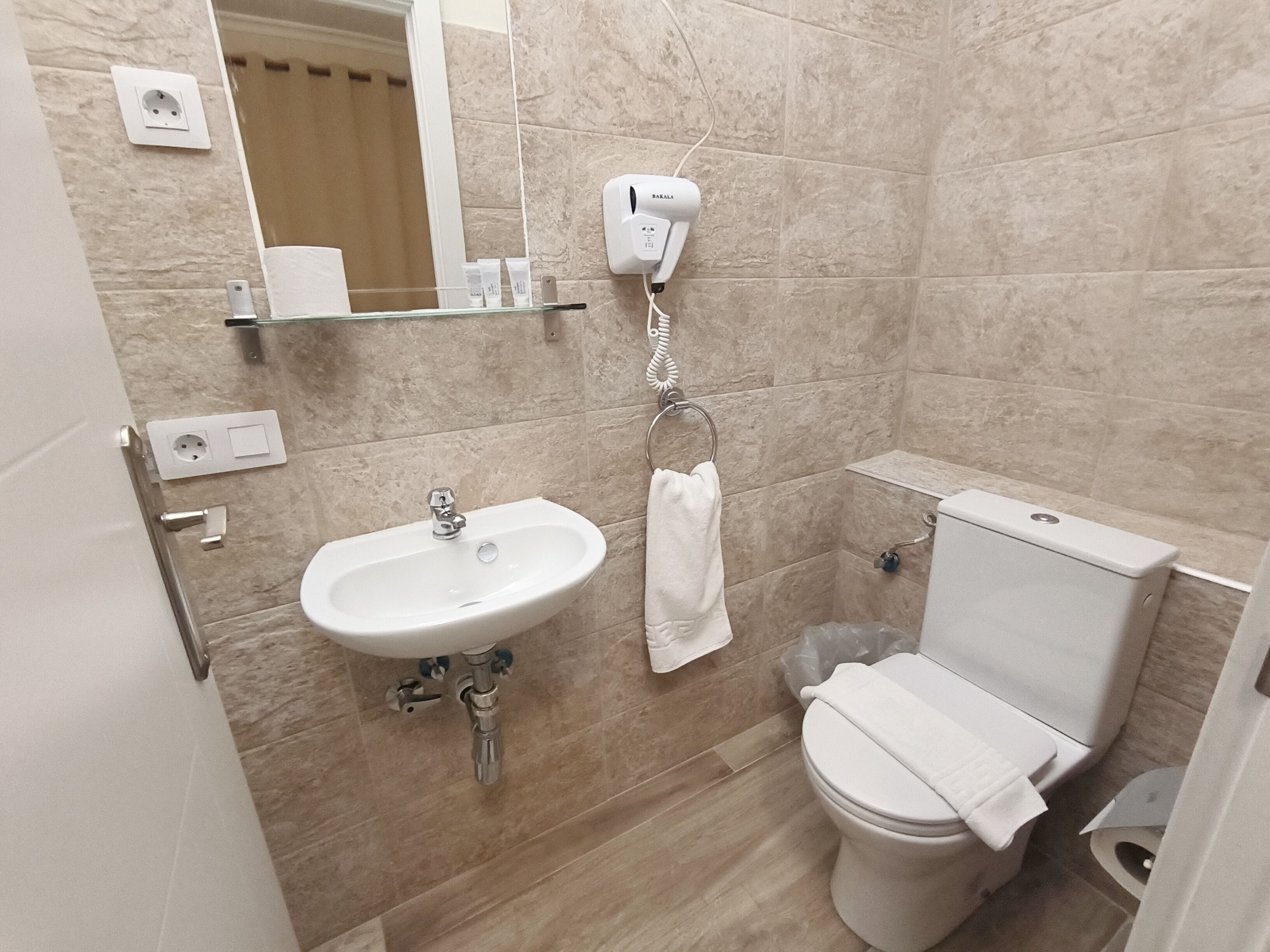 A bathroom with a sink, toilet, and hand dryer.