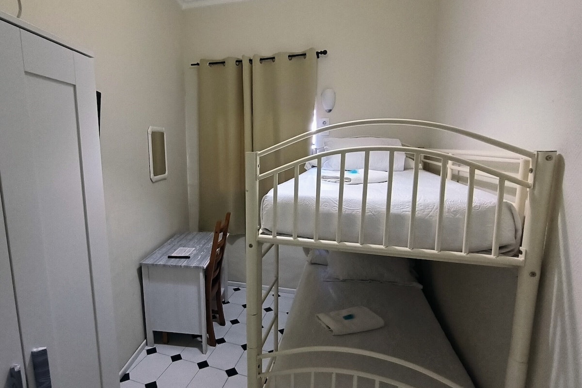 A small, compact room with a bunk bed, a desk, and a chair.