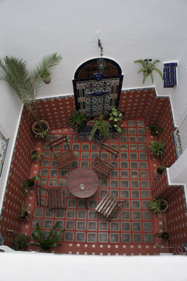 A rooftop terrace with a tiled floor, a wooden table, and several potted plants.