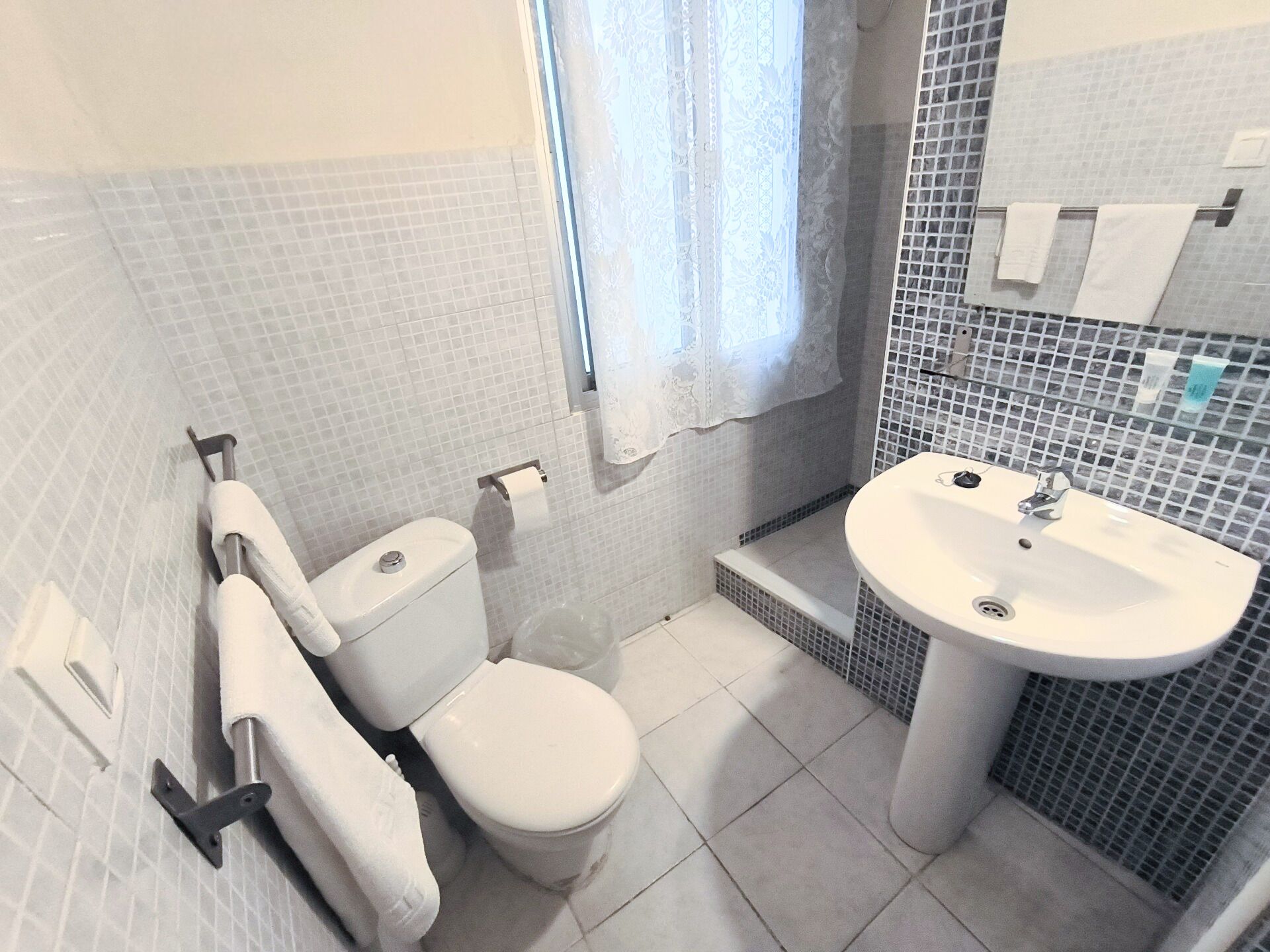 Une salle de bain avec des toilettes, un lavabo et des murs carrelés.