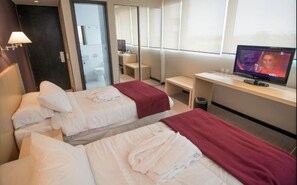 A hotel room with two beds, a TV, a desk, and a bathroom visible through a glass door. - Salto Hotel & Casino (Salto)