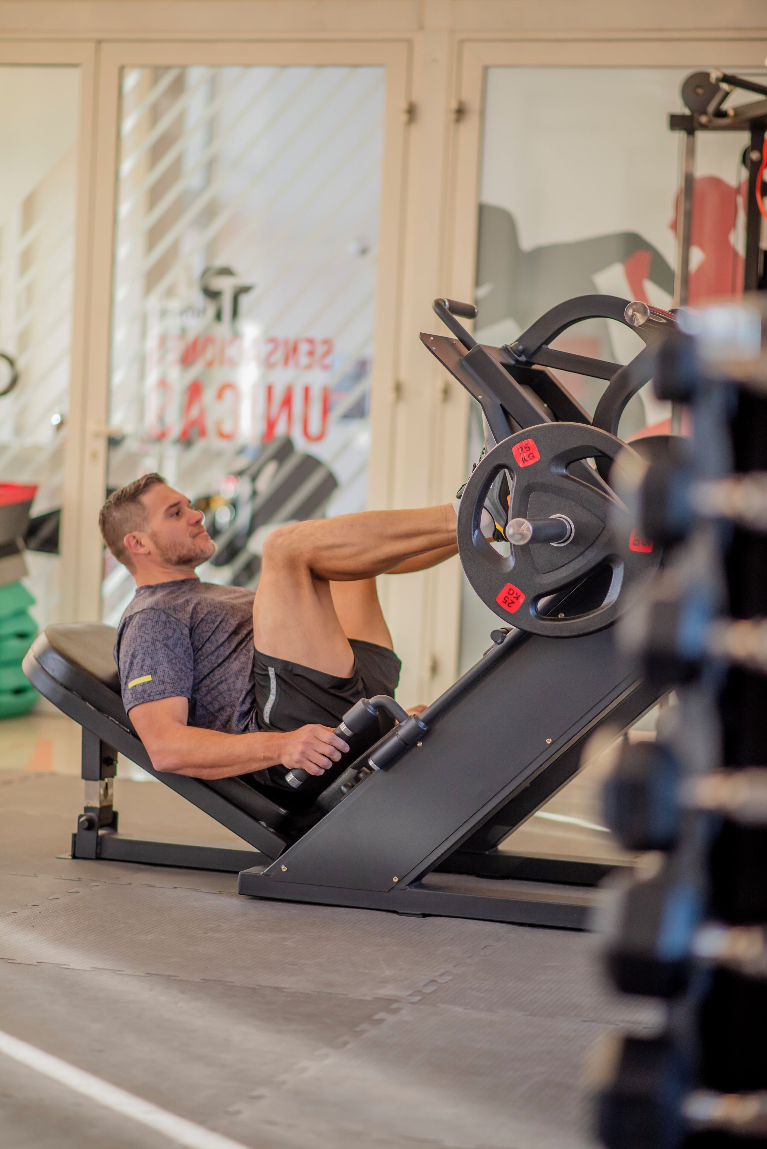 A man using a leg press machine in a gym.