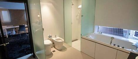 A modern bathroom with a toilet, bidet, and bathtub.
