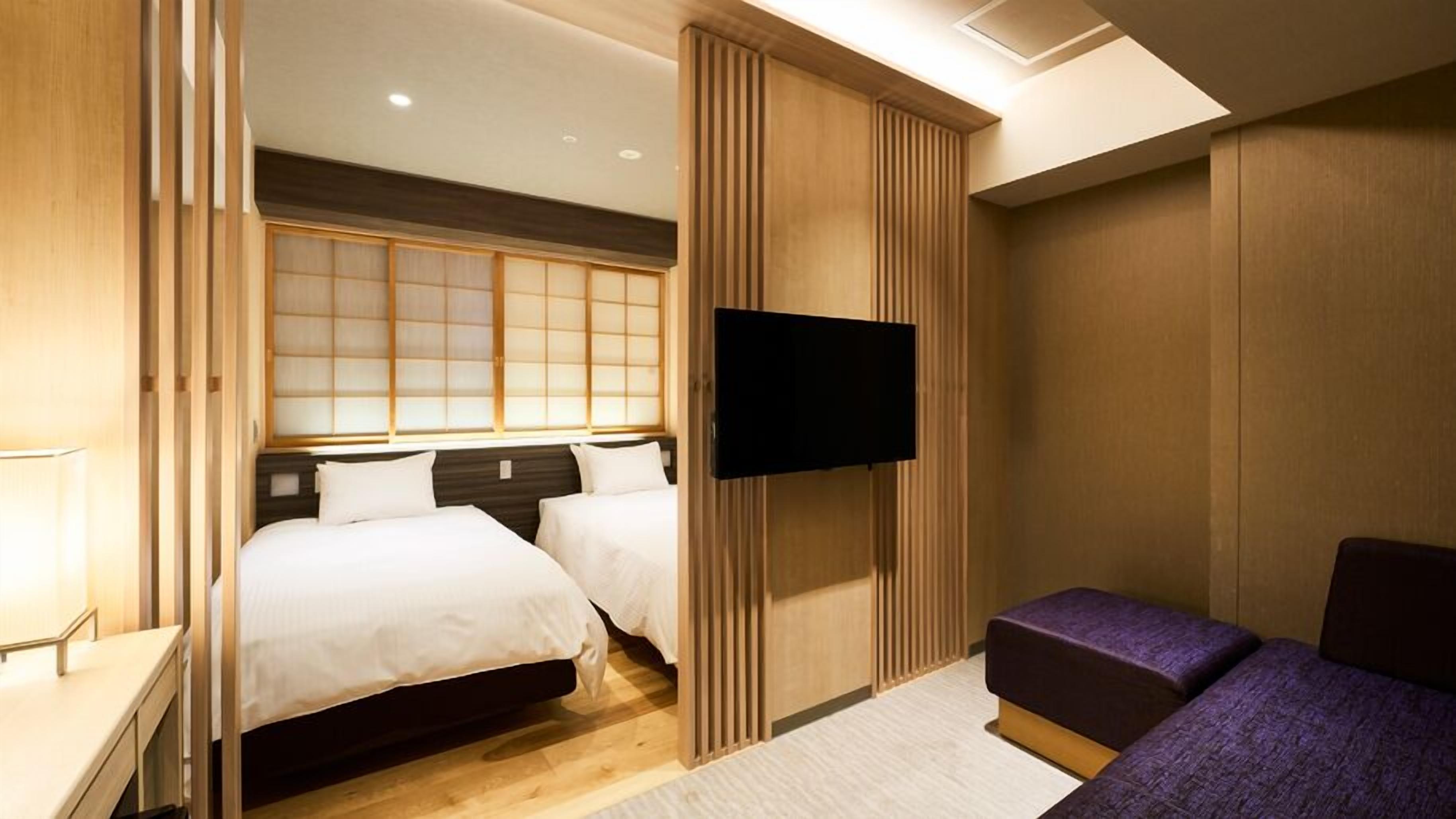 A hotel room with a bed, a TV, and a seating area.