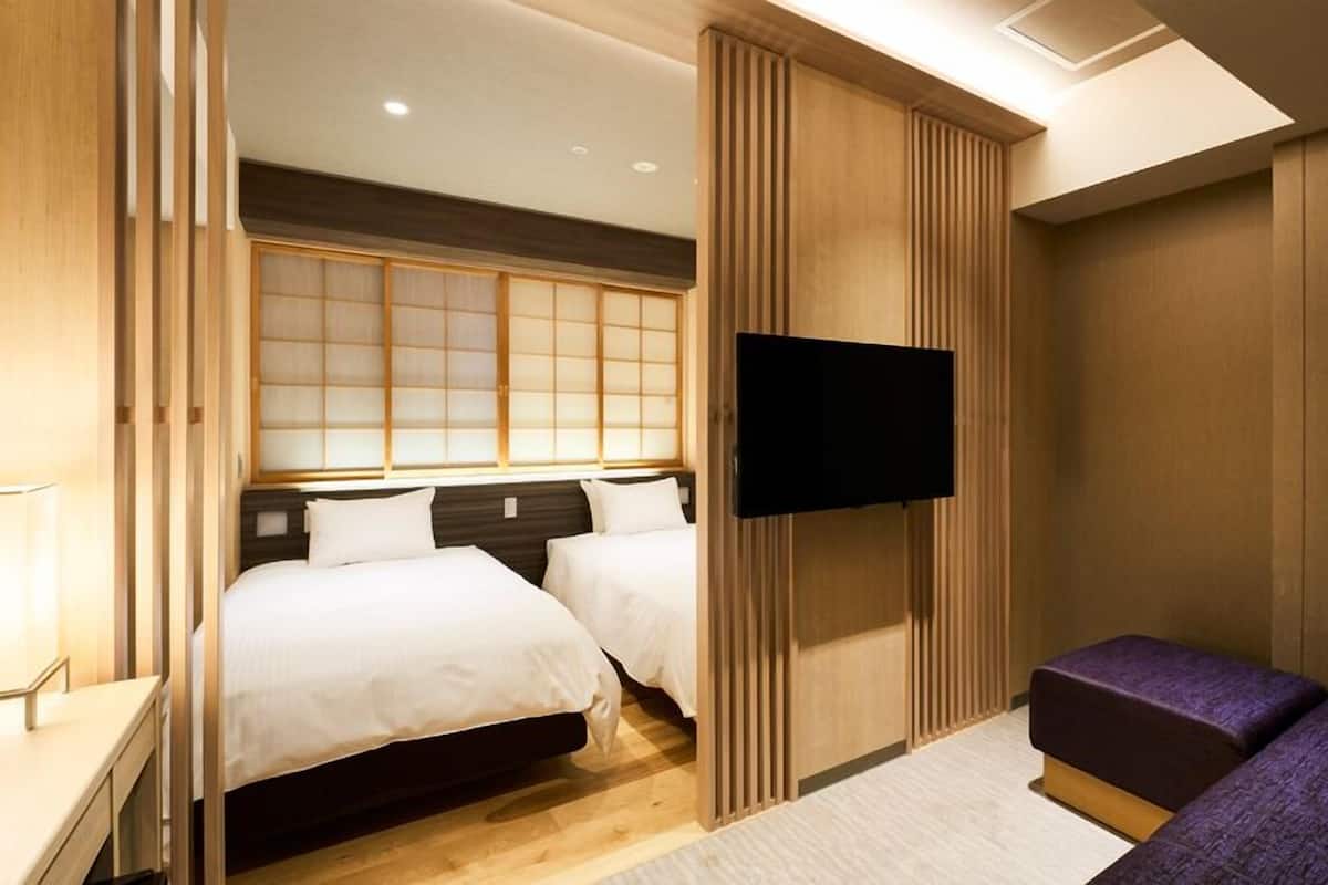 A hotel room with a bed, a TV, and a seating area.