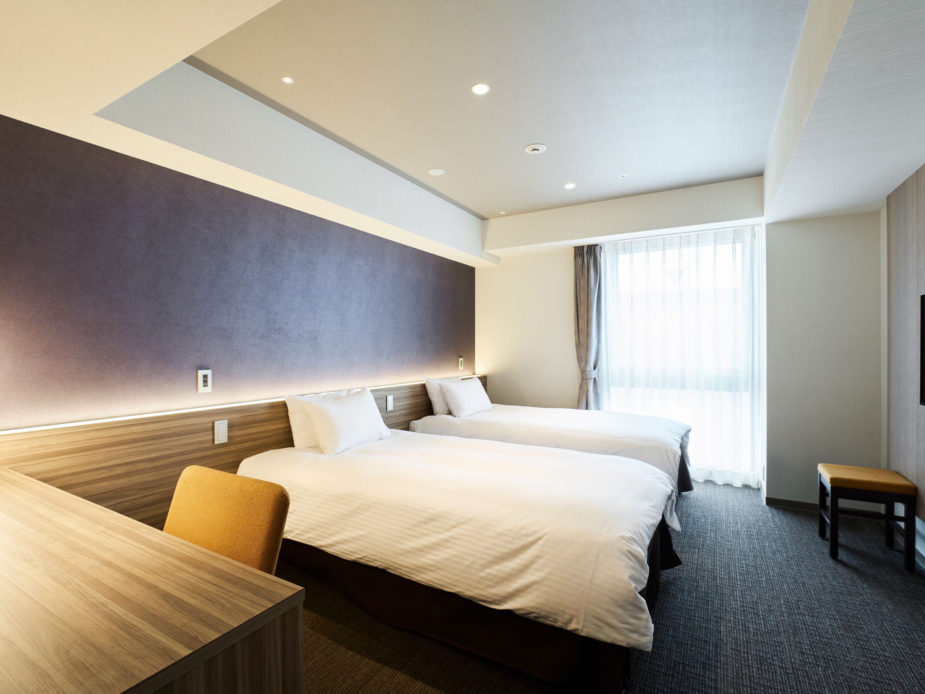 Ein Hotelzimmer mit zwei Betten, einem Schreibtisch und einem Stuhl.