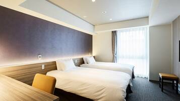 Ein Hotelzimmer mit zwei Betten, einem Schreibtisch und einem Stuhl.