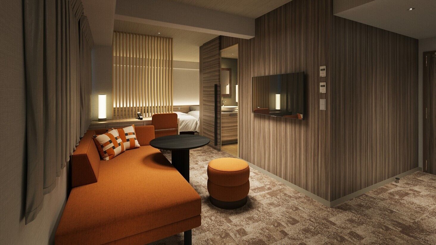A modern hotel room with a sofa, ottoman, TV, and a large mirror.