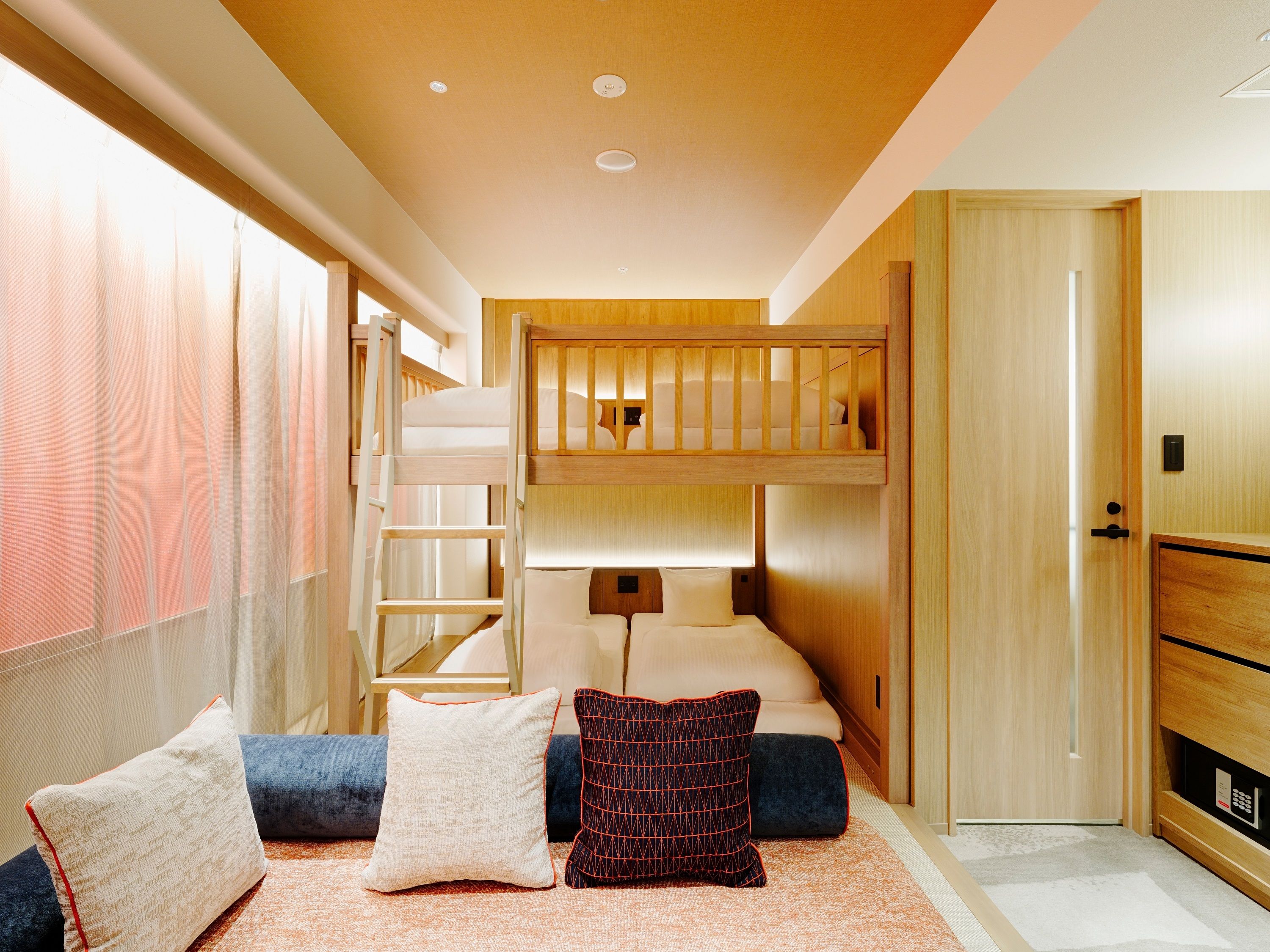 A bunk bed room with a ladder, a desk, and a wardrobe.